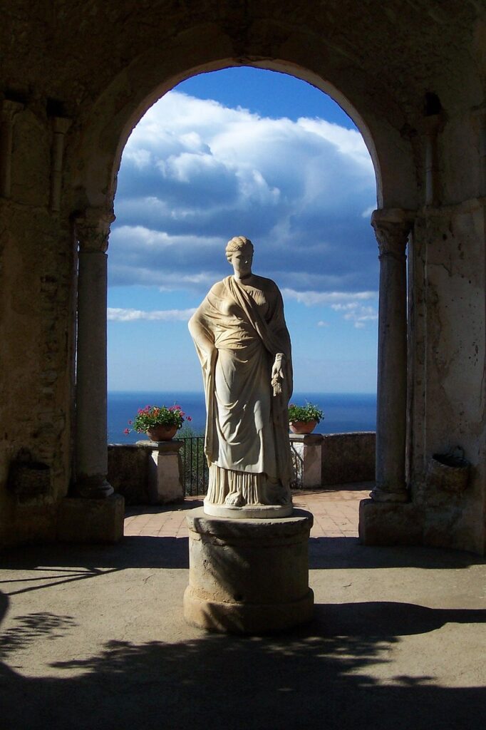 Statua classica incorniciata da un arco con il mare della Costiera Amalfitana