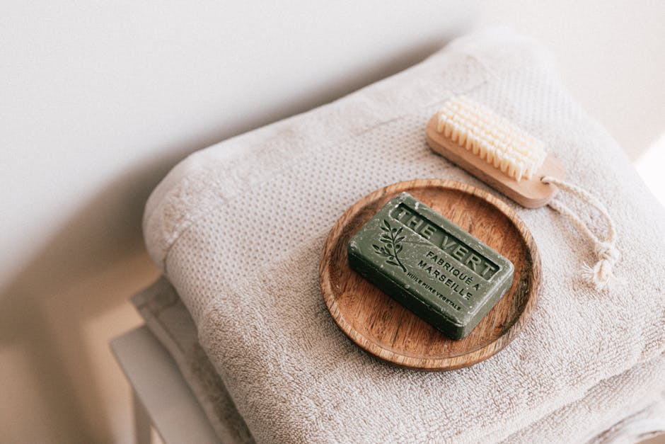 Savon vert artisanal posé sur serviette, brosse en bois à côté