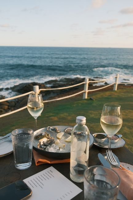 Tavolo con vini, ostriche e mare della Costiera Amalfitana sullo sfondo