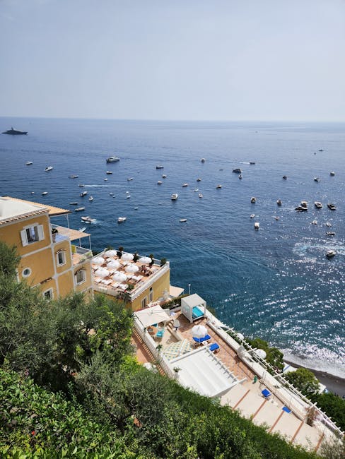 Blick auf Terrassen mit Sonnenschirmen und Boote vor der Côte amalfitaine