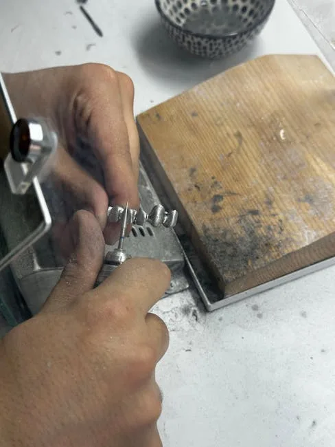 Mains d'artisan polissant un bijou en argent sur établi, atelier Palermo