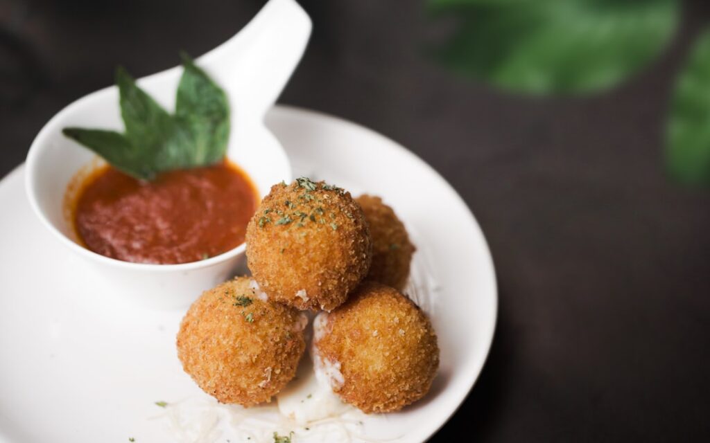 Arancini being coated in breadcrumbs
