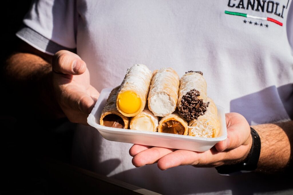 Hands filling cannoli with ricotta in Palermo