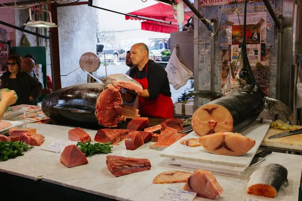 Poissonier découpe un gros thon sur le banc du marché, Palerme