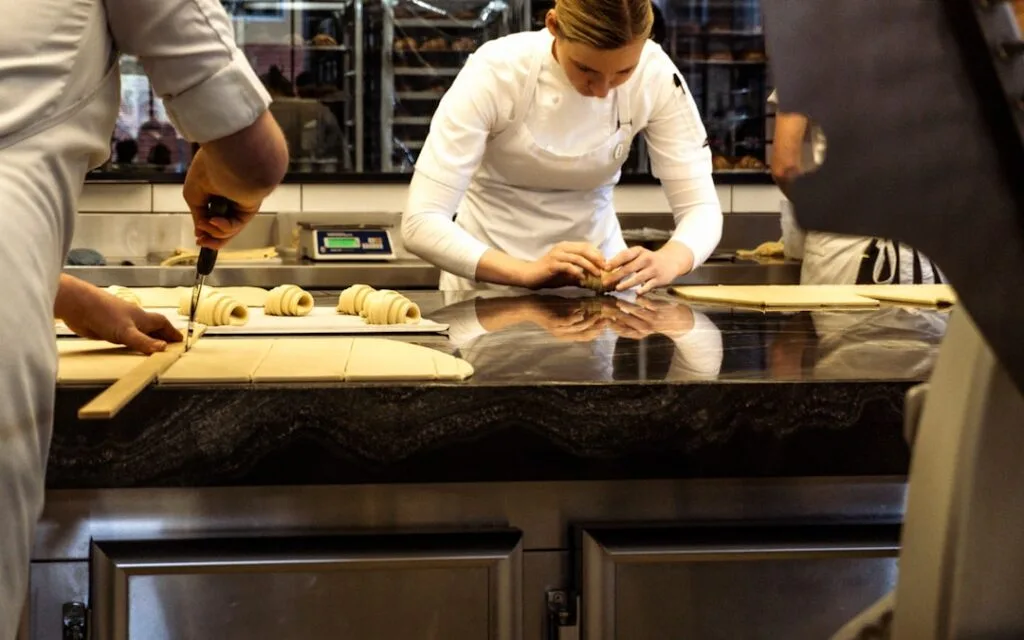 Apprenti et chef façonnant pâtes fraîches sur plan de travail dans une cuisine à Palermo