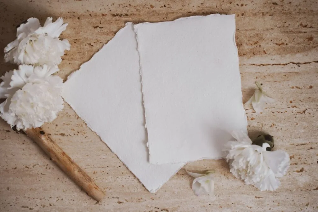 Feuilles de papier artisanal posées sur pierre, fleurs blanches, Palermo