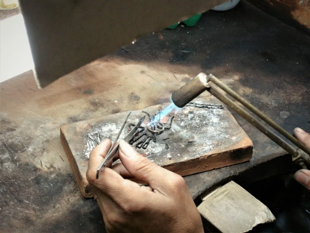Mains d'artisan chauffant un bijou au chalumeau dans un atelier de Palermo