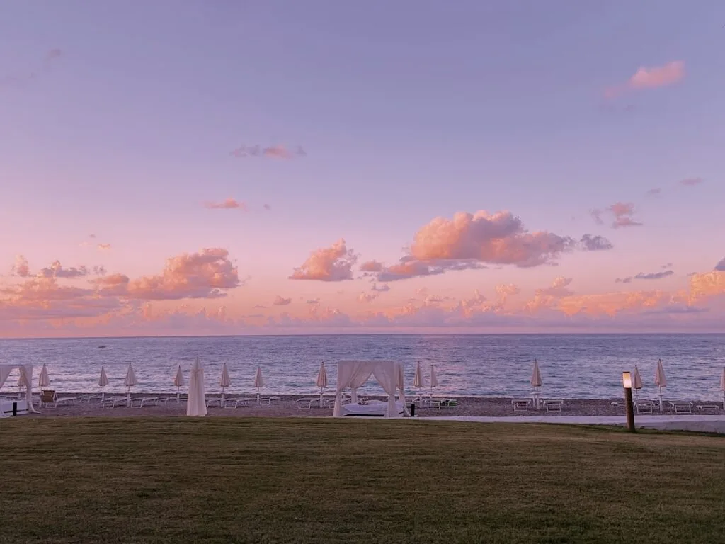 Plage d'ombrelles et ciel rose au crépuscule sur la côte de Palermo