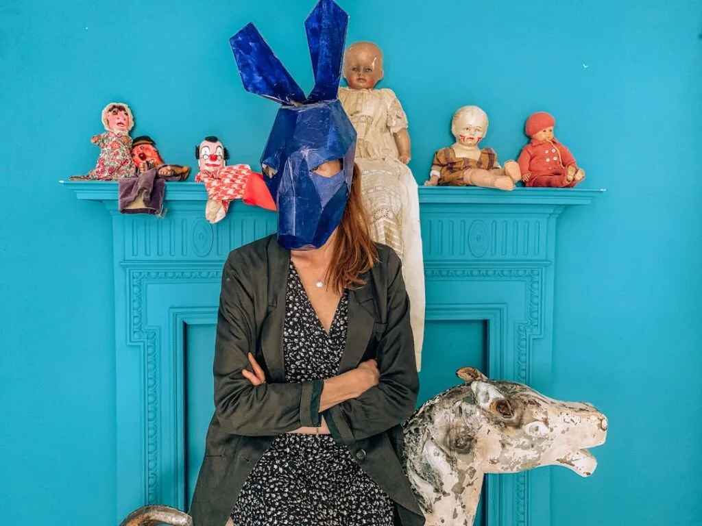 Personne masquée portant un masque bleu devant poupées, atelier à Palerme