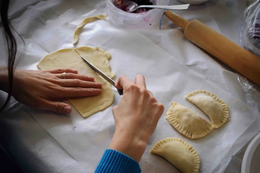Main découpant la pâte pour cannoli pendant un atelier à Palermo