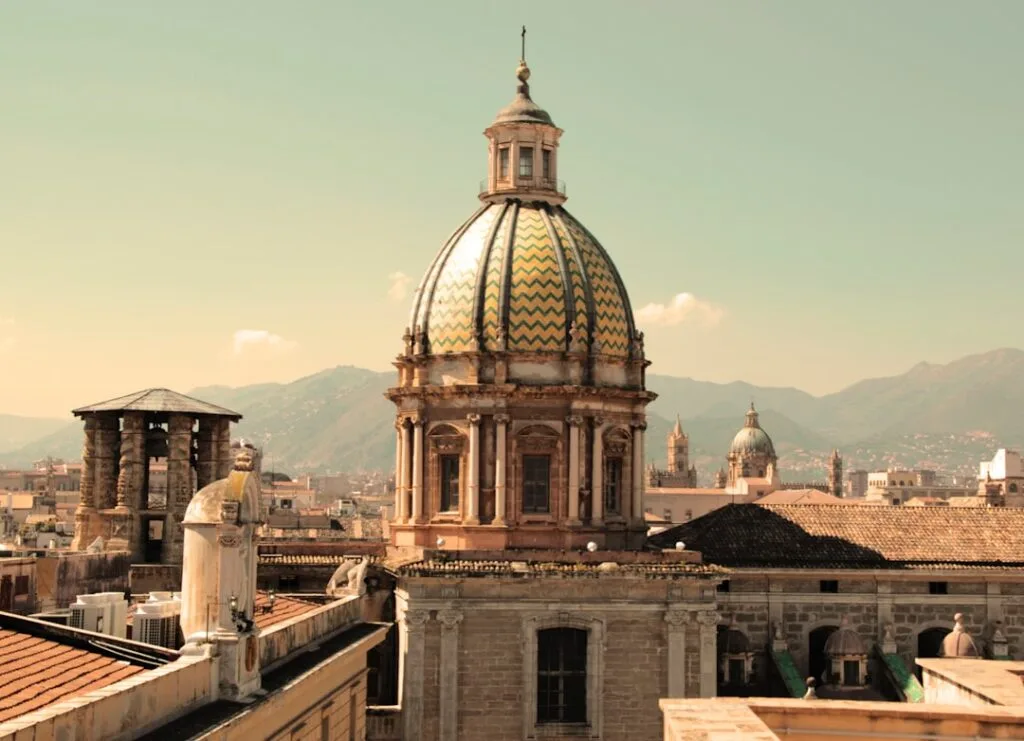 Toit en tuiles colorées d'une coupole baroque dominant les toits de Palermo