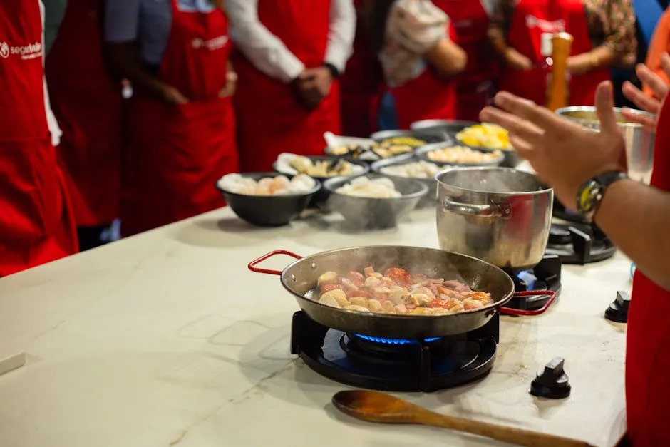 Atelier de cuisine à Palermo, participants en tabliers rouges autour d'une poêle