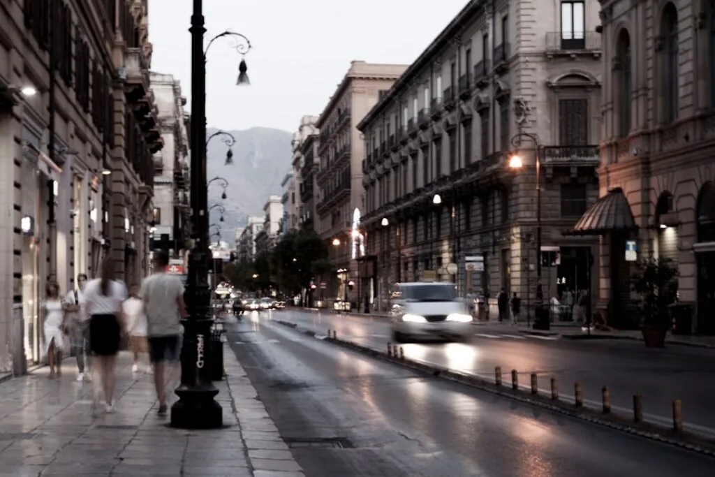 Avenue de Palermo au crépuscule, passants flous et voiture en mouvement