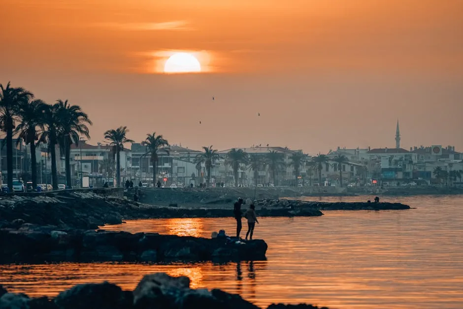 Coucher de soleil orangé sur le littoral de Palermo, silhouettes sur les rochers