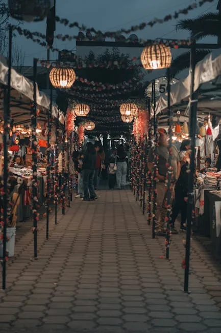 Allée d'un marché artisanal éclairée de lanternes, visiteurs en contrejour
