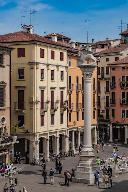 Place urbaine avec colonne centrale, terrasses et façades colorées