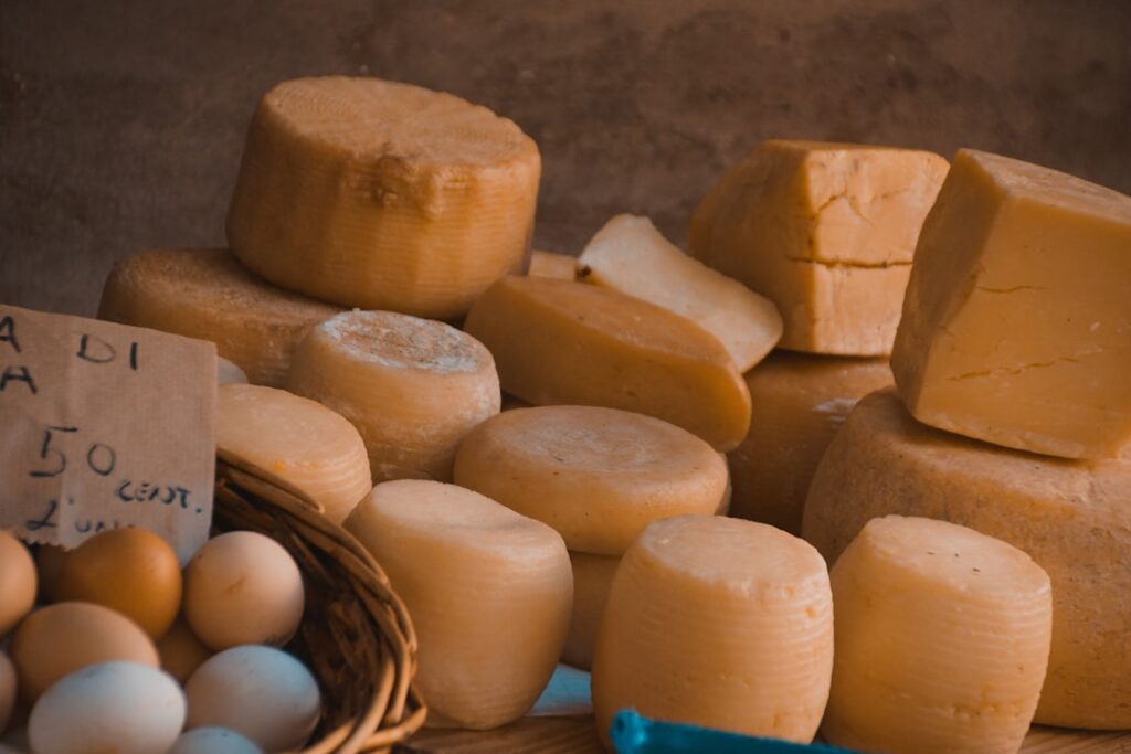 Verschiedene Käse-Laibe und Eier in Korb auf dem Markt in Matera