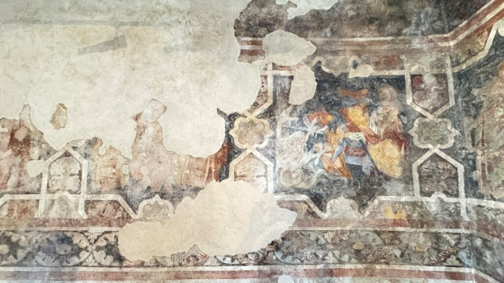 Verwittertes Freskenfragment mit geometrischem Rahmen in Matera-Höhle
