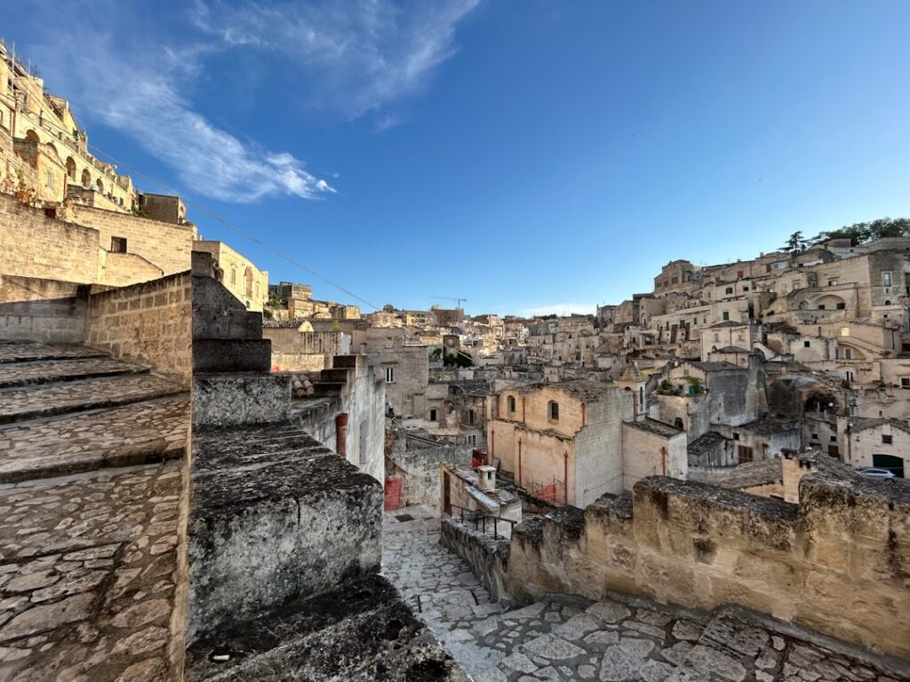 Steintreppen und Terrassen im Sassi-Viertel von Matera unter blauem Himmel.