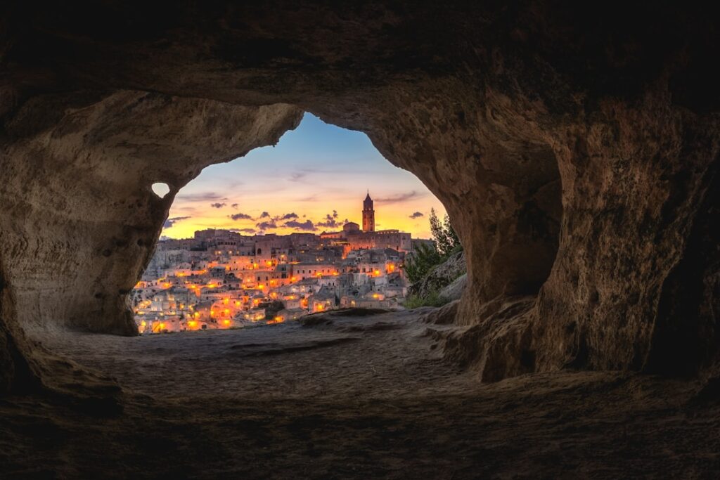 Blick aus Höhle auf abendlich beleuchtete Altstadt von Matera