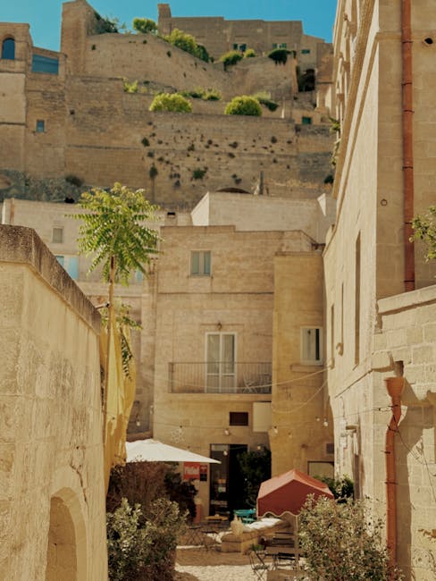 Enger sonniger Innenhof in Matera mit steinernen Häusern und Sonnenschirm