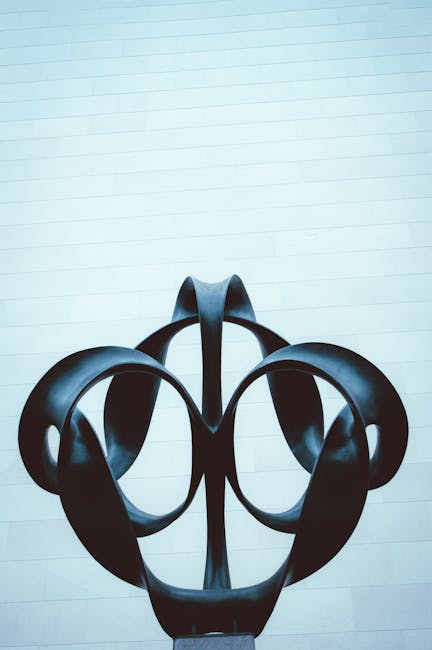 Abstrakte schwarze Skulptur vor heller Mauer, symmetrische Formen
