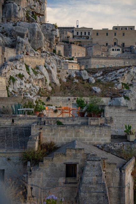 Terrassen mit orangen Stühlen und Pflanzen vor Felsen in Matera