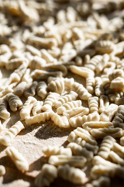 Nahaufnahme frischer handgeformter Cavatelli-Nudeln auf bemehlter Fläche.
