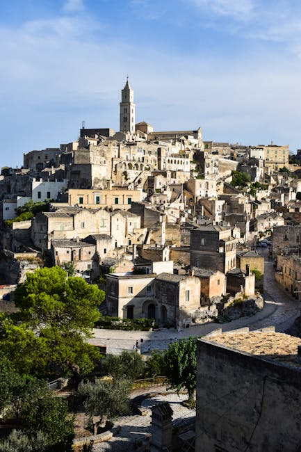 Blick auf Matera mit Turm über terrassenartigen Kalksteinhäusern.