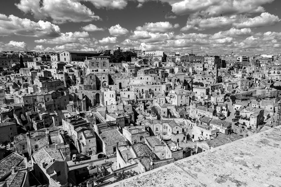 Schwarzweißes Panorama der dichtgebauten Sassi-Häuser von Matera unter Wolken.
