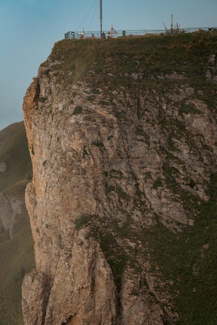 Hohe Felsklippe mit Aussichtplattform und Personen am oberen Rand.