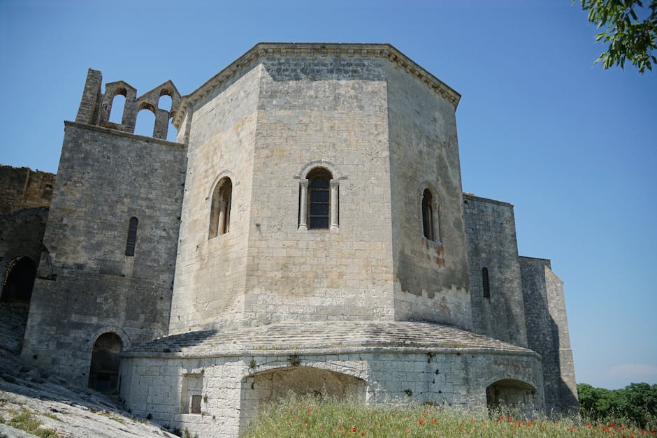 Robuste steinerne Apsis einer romanischen Kirche unter klarem Himmel.