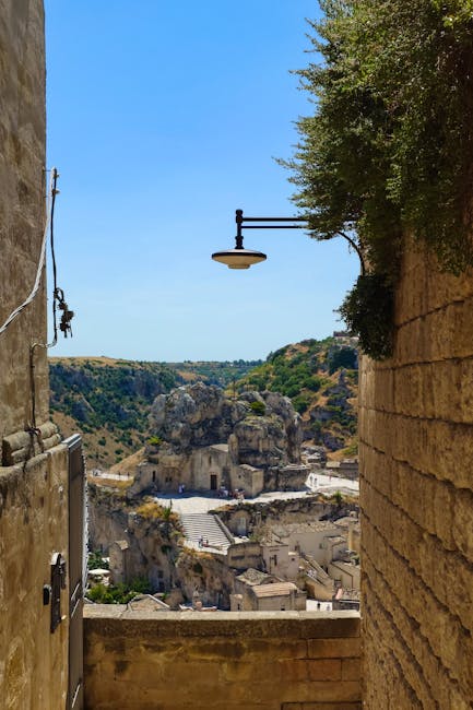 Blick durch enge Gasse auf Felskirche und Schlucht in Matera