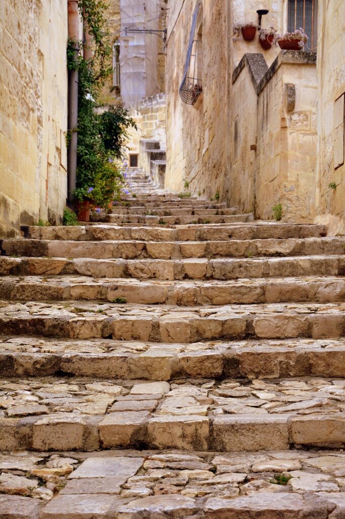Enge steinerne Treppe mit Pflanzkübeln und verwitterten Mauern in Matera.