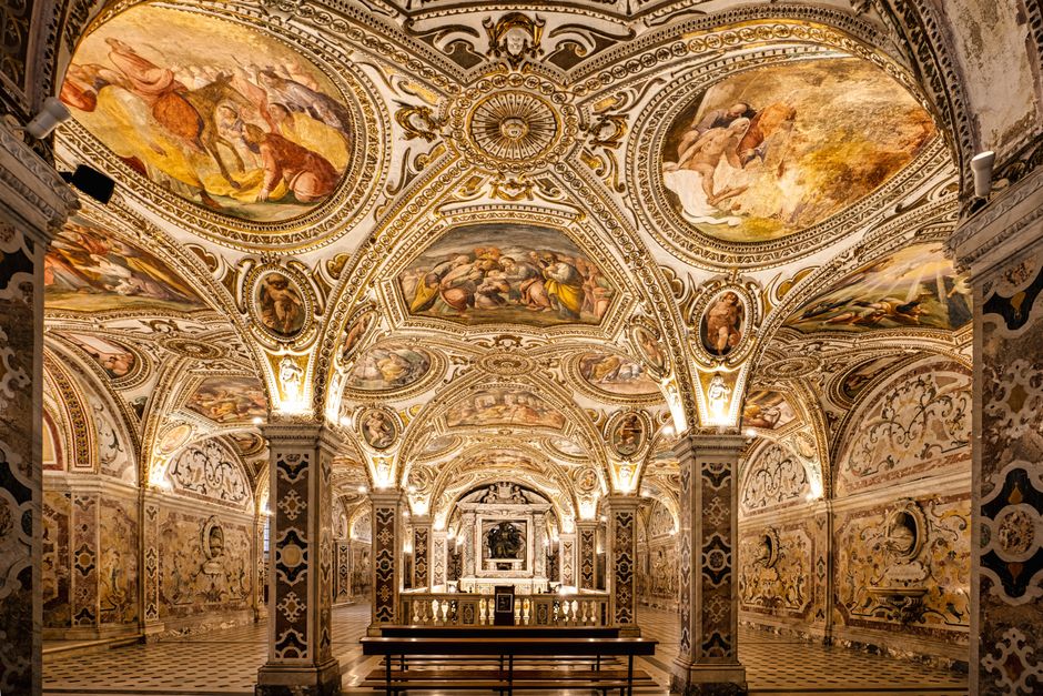 Crypte richement décorée avec voûtes peintes et colonnes illuminées à Matera