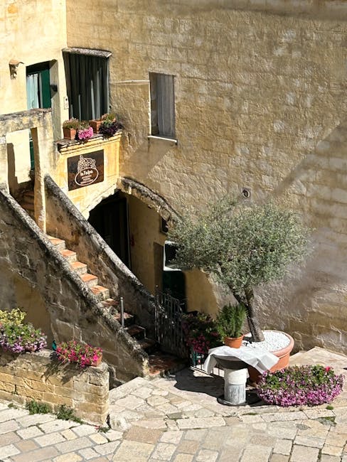 Sunlit stone stairs and potted plants in Matera's Sassi courtyard
