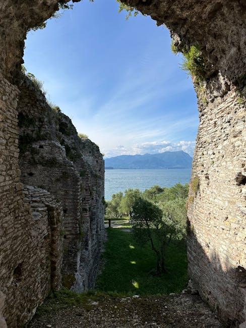 Stone arch framing olive trees and shimmering Lake Garda horizon