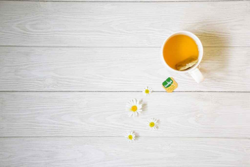 Tasse de camomille avec sachet et petites marguerites sur bois