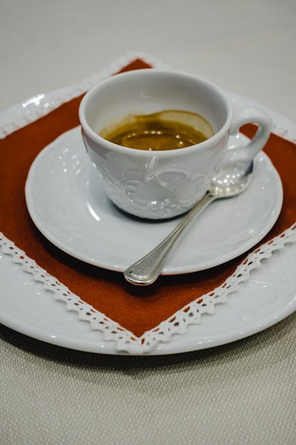 Weiße Espressotasse mit gehäkelter Spitze, Löffel auf Untertasse in Padua