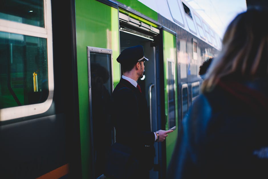 Train conductor checking passengers beside regional train at Padua station