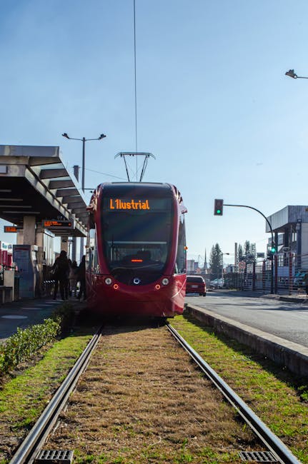 Tram rosso su rotaie fermo alla fermata urbana di Padova