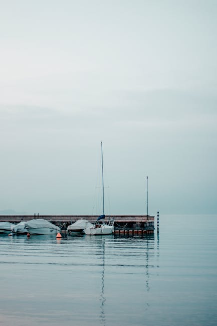 Small wooden dock with moored boats and calm Lake Garda waters