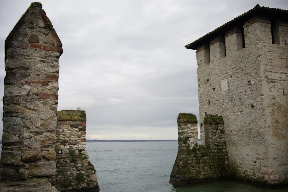 Weathered medieval stone tower and pier meeting Lake Garda waters