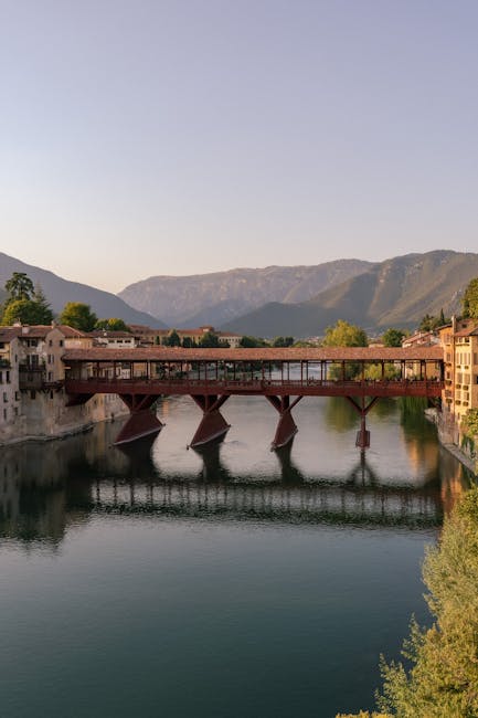 Covered wooden bridge over river in Bassano del Grappa with mountains