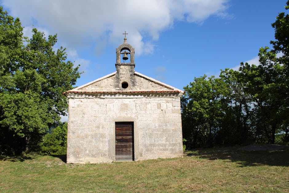 Small stone chapel with bell gable and cross amid trees near Padua
