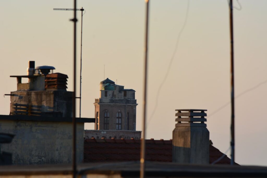 Schoorstenen en antennes op daken met toren in de verte, Padua