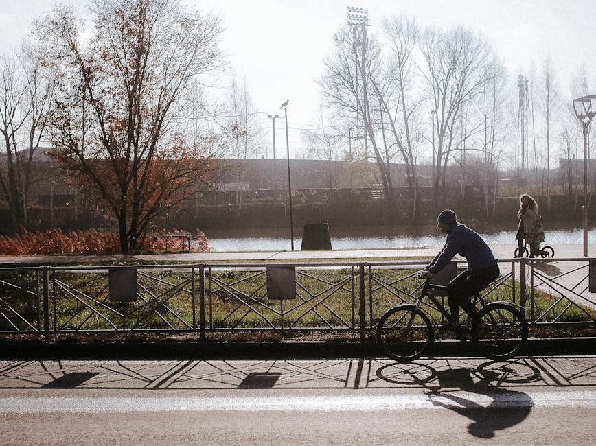 Fietser langs de rivierboulevard met hek en bomen in Padua