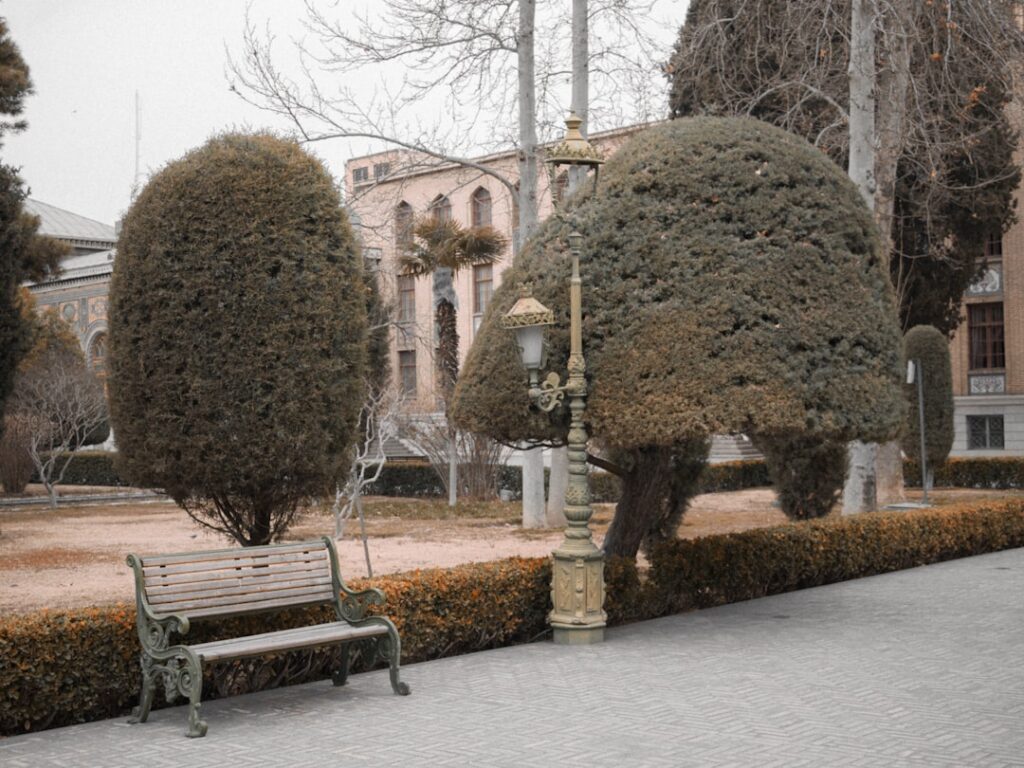 Ornate bench and lamppost among trimmed trees in Padua garden