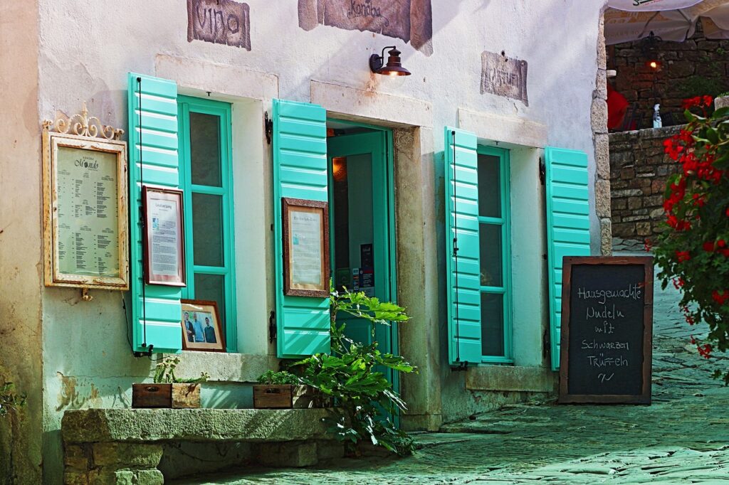 Turquoise luiken van klein restaurant aan geplaveide straat in Padua