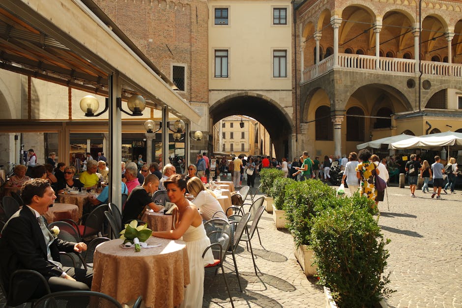 Tavoli all'aperto e persone in una piazza storica di Padova
